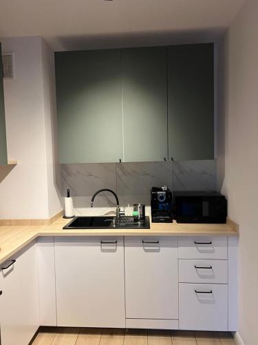 a kitchen with white cabinets and a sink and a microwave at Apartamenty Akademicka przy Onkologii 2 in Bydgoszcz