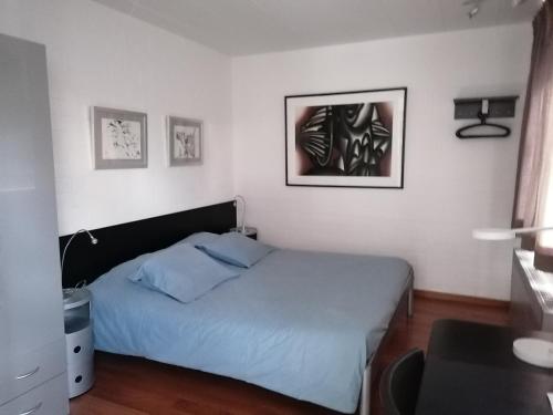 a bedroom with a bed with blue sheets and pictures on the wall at Studio's Park - Heverlee in Leuven