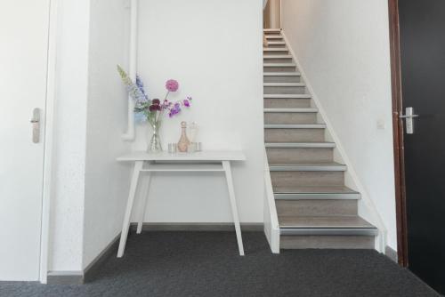 a stairway with a vase of flowers on a table at Boutique Hotel Herbergh Amsterdam Airport FREE PARKING in Badhoevedorp