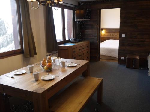 Cette chambre dispose d'une table en bois avec un bol de fruits. dans l'établissement Appartement 2 chambres avec mezzanine, piste skis aux pieds - FR-1-355-77, à Méribel