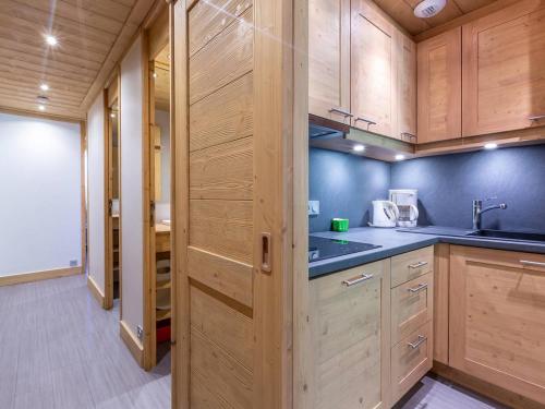 - une cuisine avec des placards en bois et des murs bleus dans l'établissement Méribel Mottaret : Apt 2 ch, terrasse, accès piste, au cœur du quartier du Laitelet - FR-1-355-167, à Les Allues