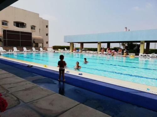 a young boy standing next to a swimming pool at Loft in Siwar 2 min from Hotel Le Royal incl motor in Adūnīs