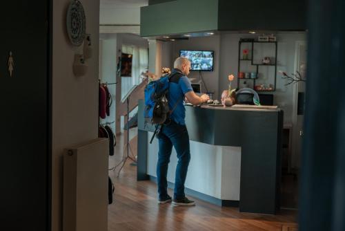 a man with a backpack standing at a counter at Boutique Hotel Herbergh Amsterdam Airport FREE PARKING in Badhoevedorp