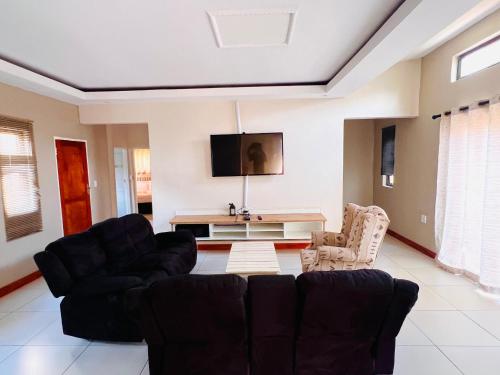 a living room with two couches and a tv at Lamamie Suite Lodge in Thohoyandou