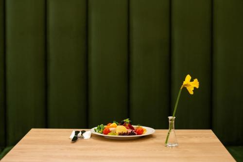 a table with a plate of food and a vase with a flower at Hotel Epic Centrum in Cisnădie