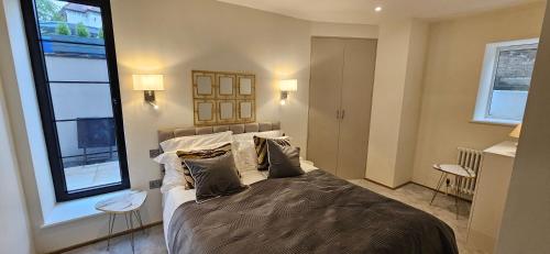 a bedroom with a large bed and two windows at Stylish new 2 bedroom apartment in London
