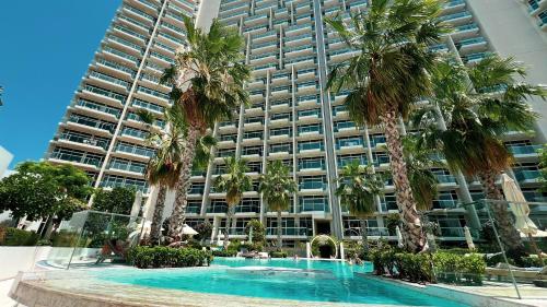 a large building with palm trees in front of a swimming pool at SmartStay at Zaya Hameni - Modern Luxury Apartments - Unique in JVC in Dubai