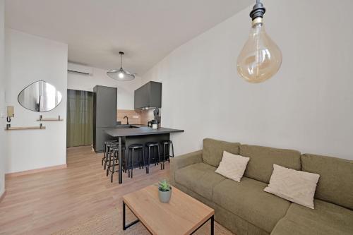 un soggiorno e una cucina con un divano e un tavolo di Emile - Apt avec Clim intra muros ad Avignone