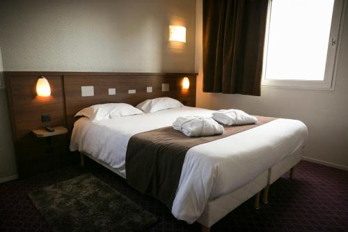 a hotel room with a large bed with two towels on it at Brit Hotel Rennes Le Castel in Rennes