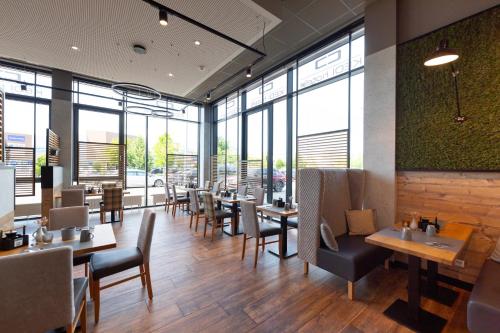 a restaurant with tables and chairs and windows at Kedi Hotel Papenburg in Papenburg