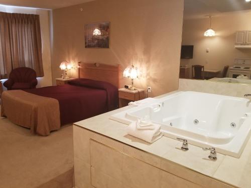 a bathroom with a tub and a bedroom with a bed at New Imperial Suites in Whitecourt
