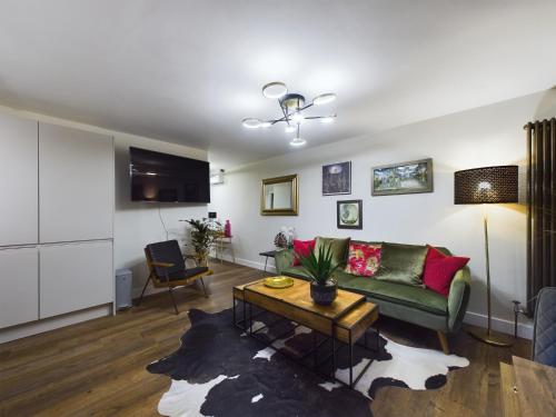 a living room with a green couch and a table at Islington Lux garden flat moments to tube in London