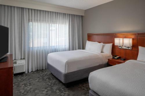 a hotel room with two beds and a television at Courtyard by Marriott Nashville Airport in Nashville