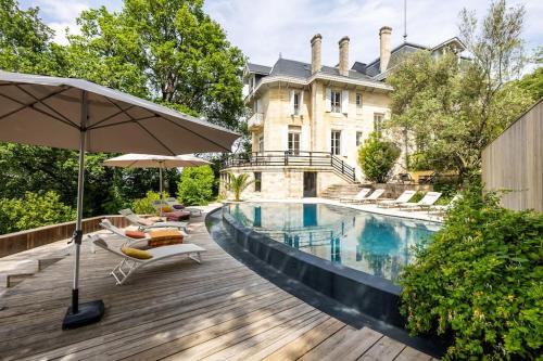 - une piscine en face d'une maison avec des chaises et un parasol dans l'établissement Chalet Baron, à 15 min de Bordeaux, à Lormont
