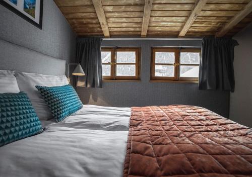 a bedroom with a large bed with two blue pillows at Langley Hotel Gustavia in Chamonix