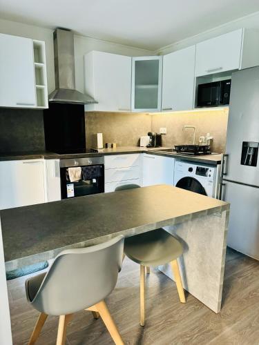 une cuisine avec des armoires blanches et une table et des chaises dans l'établissement Moderne Cosy T2 à Évry, à Étiolles
