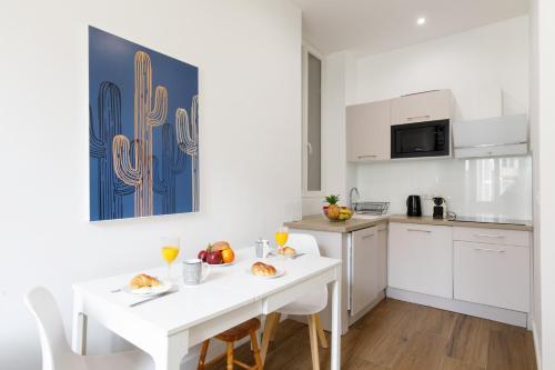une cuisine blanche avec une table et des chaises blanches dans l'établissement L'Elégant YourHostHelper, à Cannes