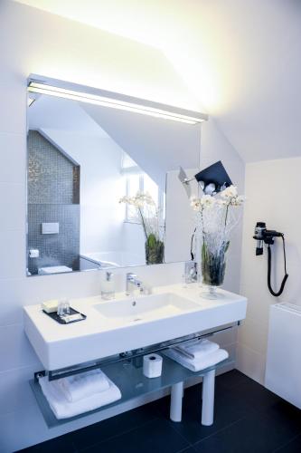 a white bathroom with a sink and a mirror at Myo Hotel Mysterius in Prague