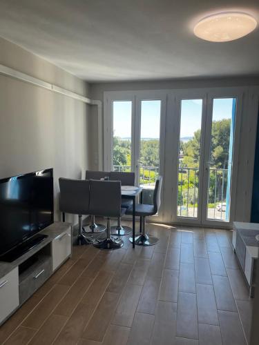 a living room with a table and chairs and a television at Appartement, vue sur l’étang, proche aéroport. in Vitrolles