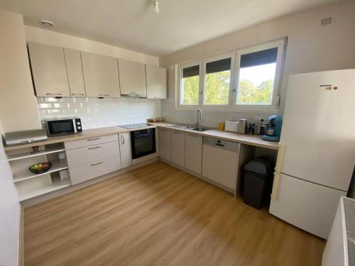 une cuisine avec des armoires blanches et un plancher en bois dans l'établissement Campagne à la Ville, à Montbéliard