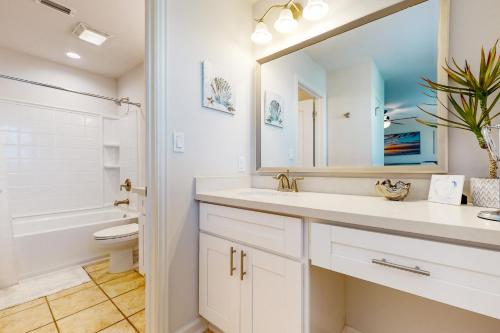 Un baño con lavabo, inodoro y espejo. en Baydreaming, en Rockport