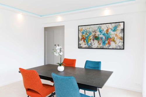 une salle à manger avec une table noire et des chaises colorées dans l'établissement Great 3bedrooms 100m from Croisette, à Cannes