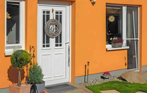 an orange house with a white door and a window at Lassan, Ferienwohnung zum Peenestrom in Lassan