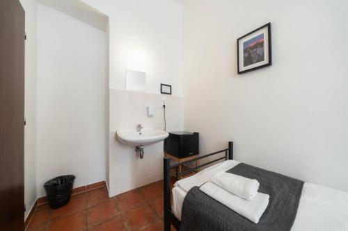 a bathroom with a bed and a sink in a room at Pension 15 Homér in Prague