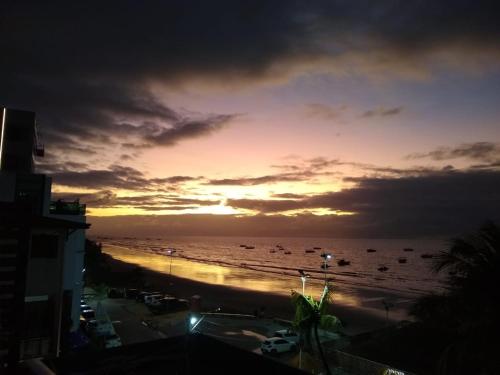 a sunset over a beach with boats in the water at Pousada Tropical Maragogi in Maragogi