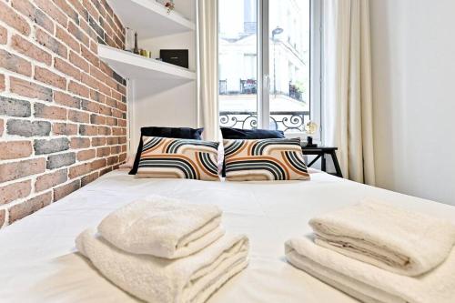 un lit dans une chambre avec un mur de briques dans l'établissement Petit studio confortable et central #marais - II, à Paris