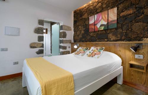 a bedroom with a white bed and a stone wall at Apartamento Los 4 Nobles in Tinajo