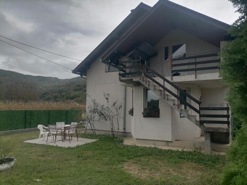 a white house with a table and a staircase at Kuća za odmor IN Bajina Basta in Bajina Bašta