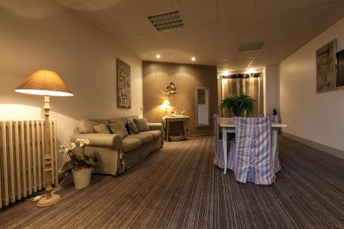 a living room with a couch and a table at Brit Hotel Bristol Montbéliard Centre in Montbéliard