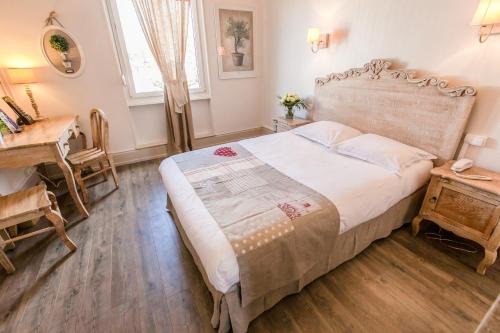 a bedroom with a bed and a table and a desk at Brit Hotel Bristol Montbéliard Centre in Montbéliard