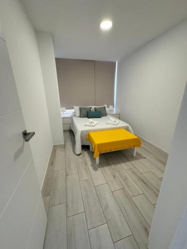 a room with a bed and a yellow bench in it at Vistas Plaza España centro ciudad Las Palmas in Las Palmas de Gran Canaria