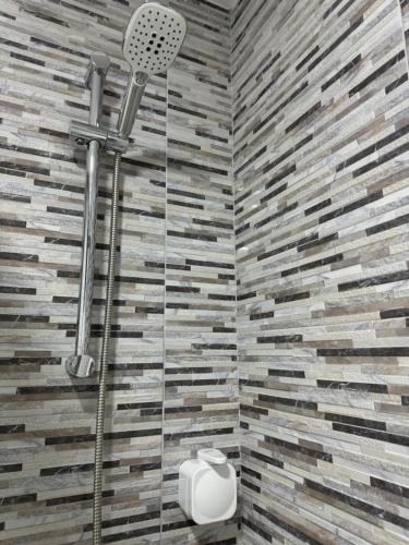 a shower in a bathroom with a stone wall at Vistas Plaza España centro ciudad Las Palmas in Las Palmas de Gran Canaria