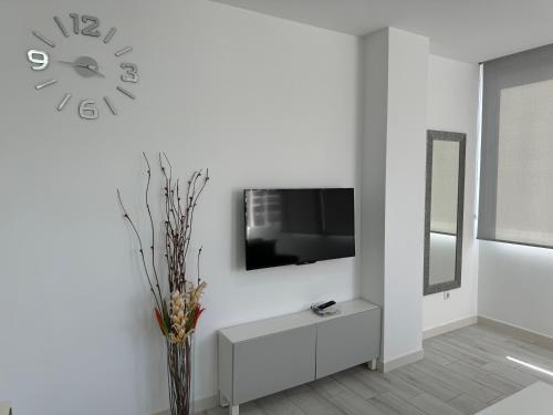 a white living room with a clock on the wall at Vistas Plaza España centro ciudad Las Palmas in Las Palmas de Gran Canaria