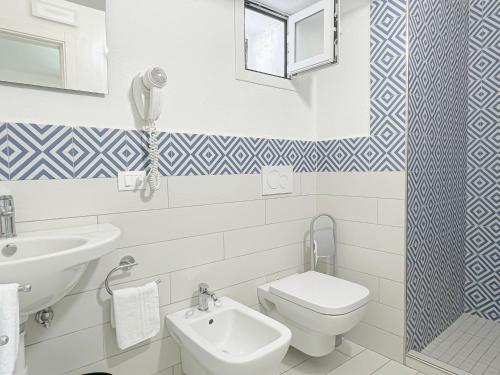a bathroom with a white toilet and a sink at Hotel Lord Byron in Ischia