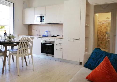 a kitchen and dining room with white cabinets and a table at Holihome - Appartamento LA GIOIA in Tortoreto Lido