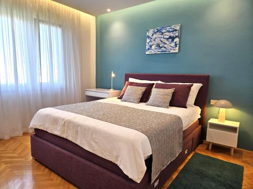 a bedroom with a large bed with a blue wall at Apartment Olga in Malinska