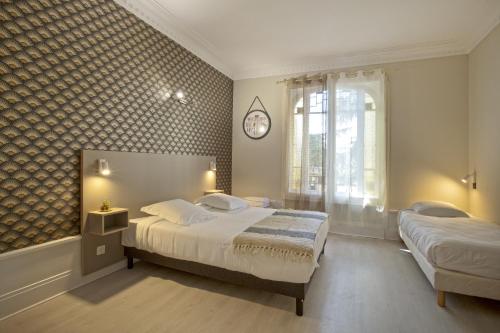a bedroom with two beds and a clock on the wall at GAB HOUSE - Lyon Bron - Eurexpo City Living Stay in Bron