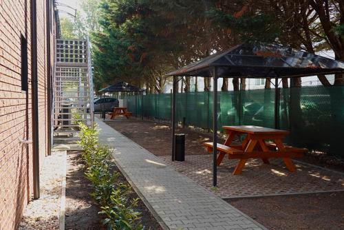a picnic table under a canopy next to a fence at Comfort Housing Apartments in Falkensee