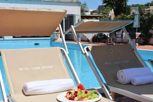 a table with two chairs and a plate of fruit at Hotel Lord Byron in Ischia