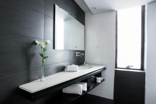 a bathroom with a sink and a vase with flowers at Urbanica The Libertador Hotel in Buenos Aires