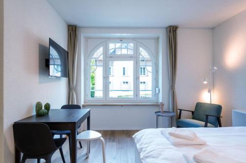 a bedroom with a bed and a desk and a window at HITrental Riesbach Apartments in Zürich