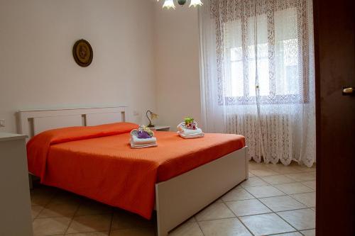 a bedroom with a bed with orange sheets and a window at Apartments Delise in Scardovari