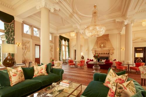 a large living room with green couches and a chandelier at Down Hall Hotel in Bishops Stortford