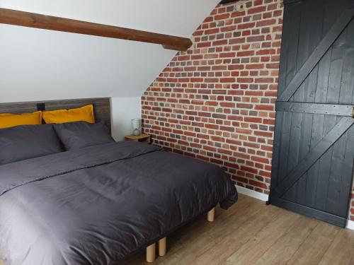 une chambre avec un lit et un mur de briques dans l'établissement Au 112 maison d'hôtes, à Estrées-Saint-Denis