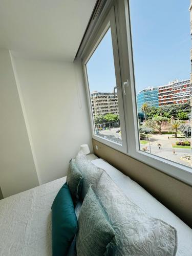 a bed with pillows in a room with a window at Vistas Plaza España centro ciudad Las Palmas in Las Palmas de Gran Canaria
