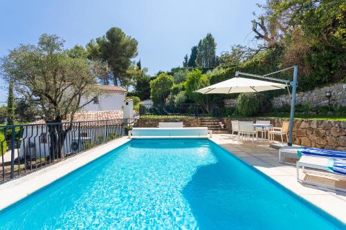 - une piscine avec un parasol, une table et des chaises dans l'établissement VILLA LA ROSERAIE VI4425 By Riviera Holiday Homes, à Mougins